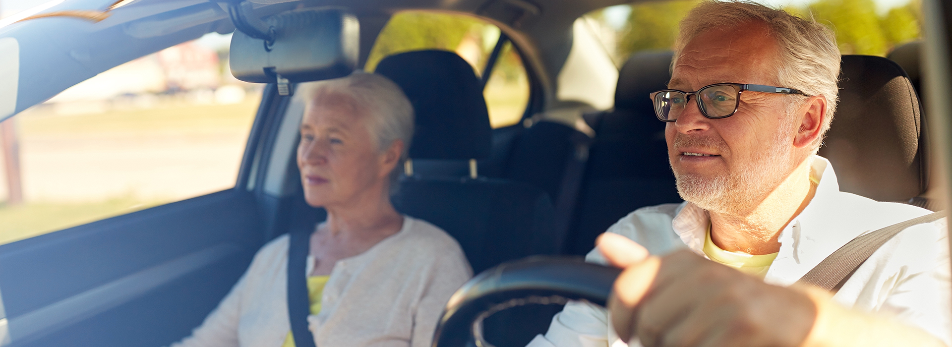 Oudere man en vrouw rijden in auto na verlengen rijbewijs